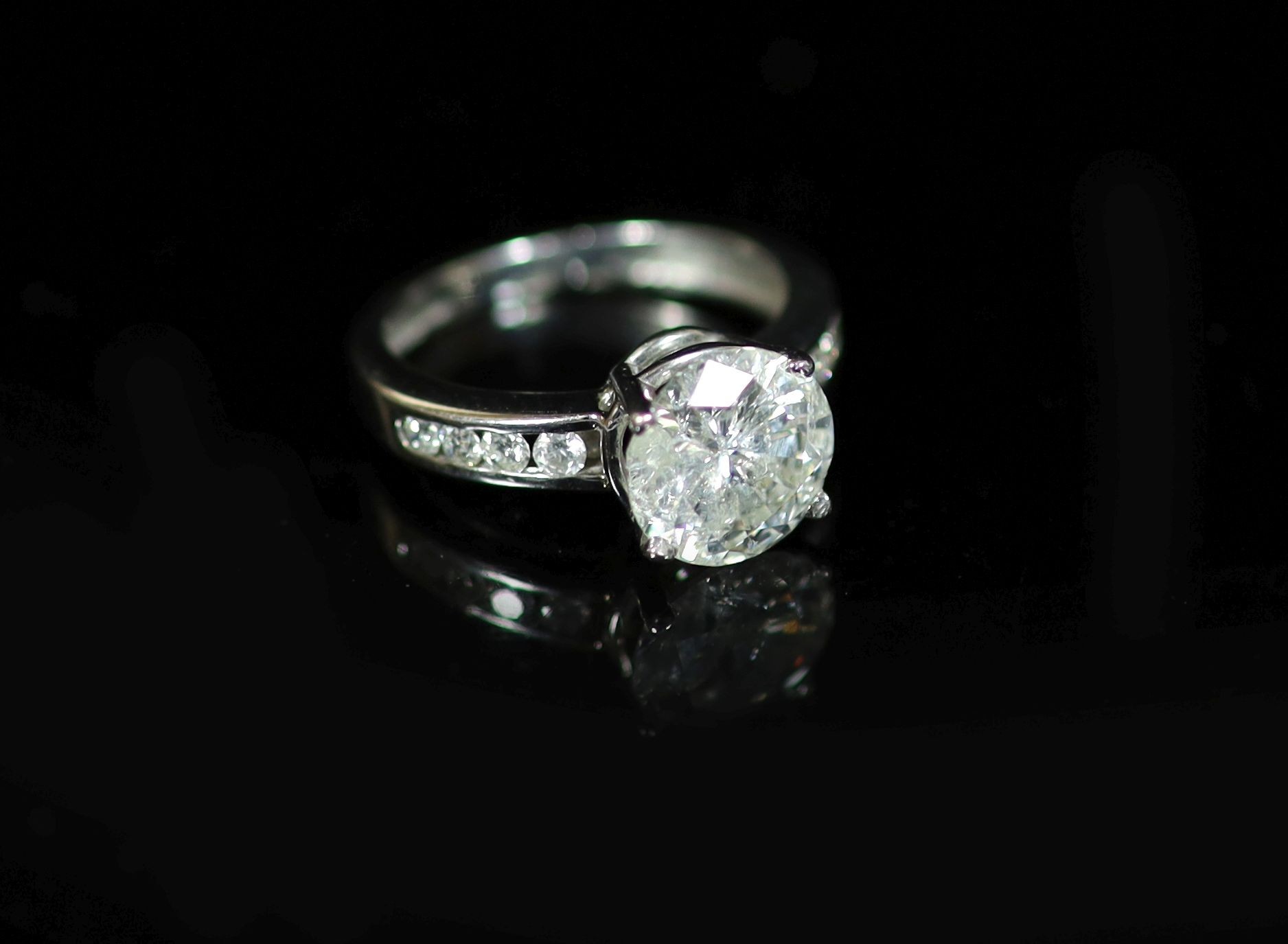 A modern white gold and single stone diamond ring, with eight stone diamond set shoulders